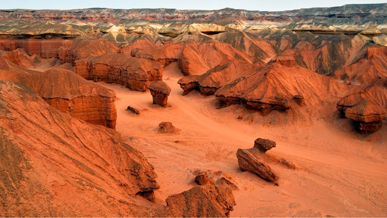 Formações rochosas coloridas e paisagem desértica em um cânion sob um céu claro.